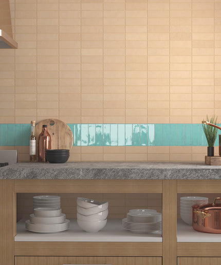 Modern kitchen backsplash with beige subway tiles and aqua accent strip behind countertop.