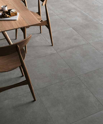 Modern dining area with large gray porcelain floor tiles and wooden table chairs