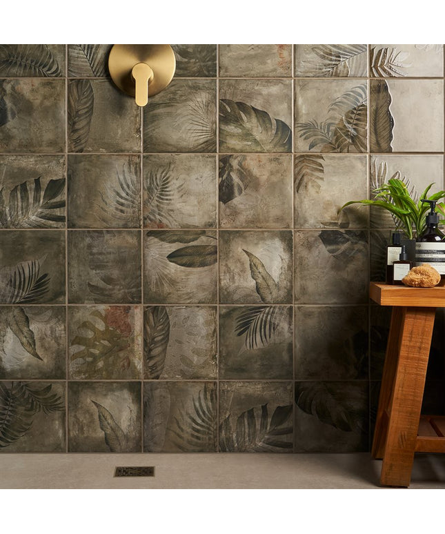 Bathroom with tiled wall featuring leaf patterns and a wooden stool with plants.