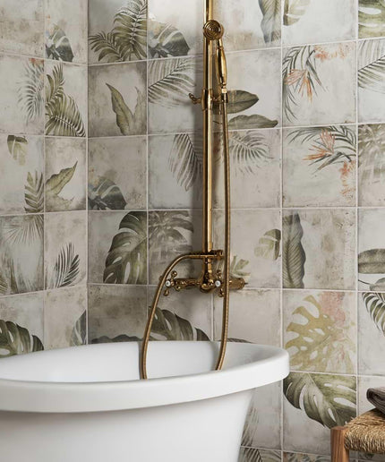 Bathroom with a freestanding bathtub against a wall of decorative tiles with leaf patterns.