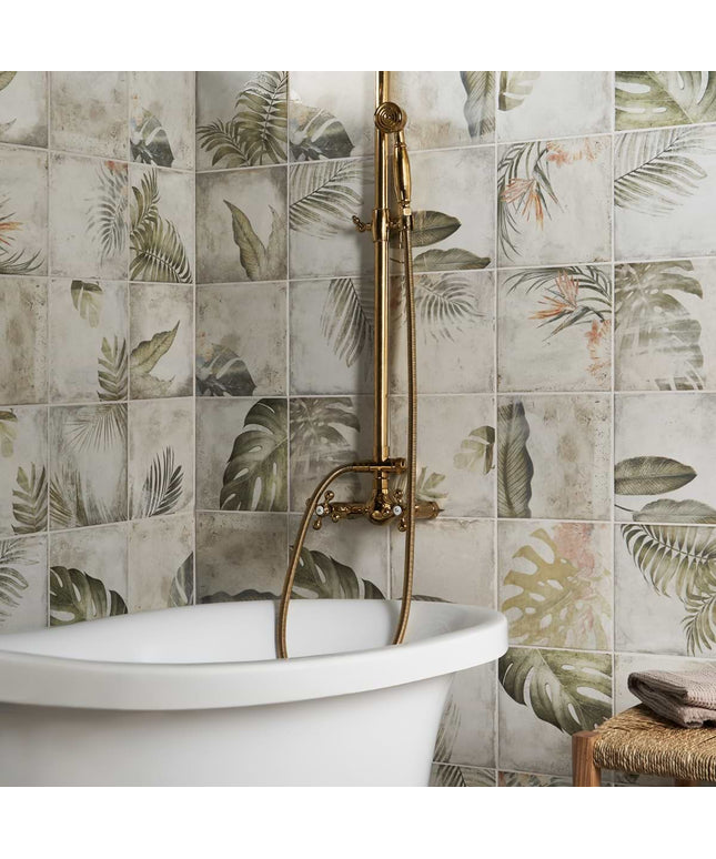 Bathroom with a freestanding bathtub against a wall of decorative tiles with leaf patterns.