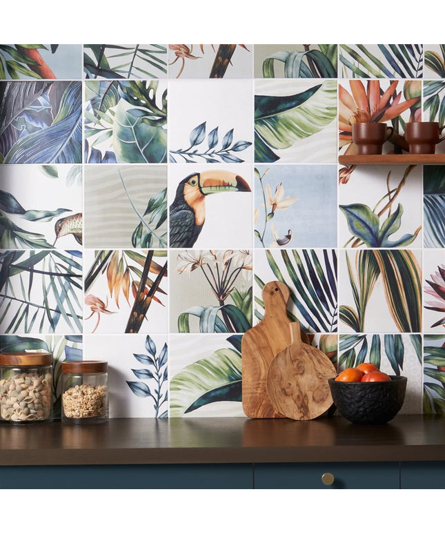 Tropical-themed kitchen backsplash with toucan and leaf patterns, wooden cutting board, and fruit bowl.