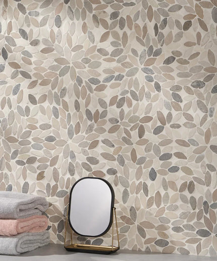 Leaf-patterned natural stone mosaic tile wall with stacked towels and tabletop mirror