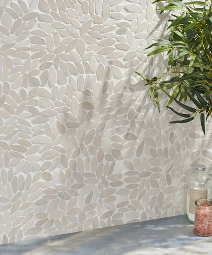 White floral mosaic tile wall with a potted plant and candle on a gray floor