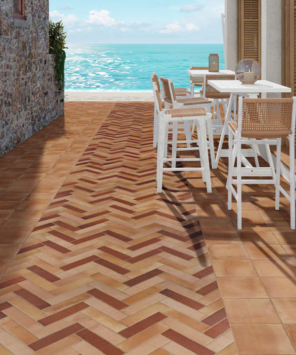 Outdoor seating area with tables and chairs on a wooden deck overlooking the ocean.