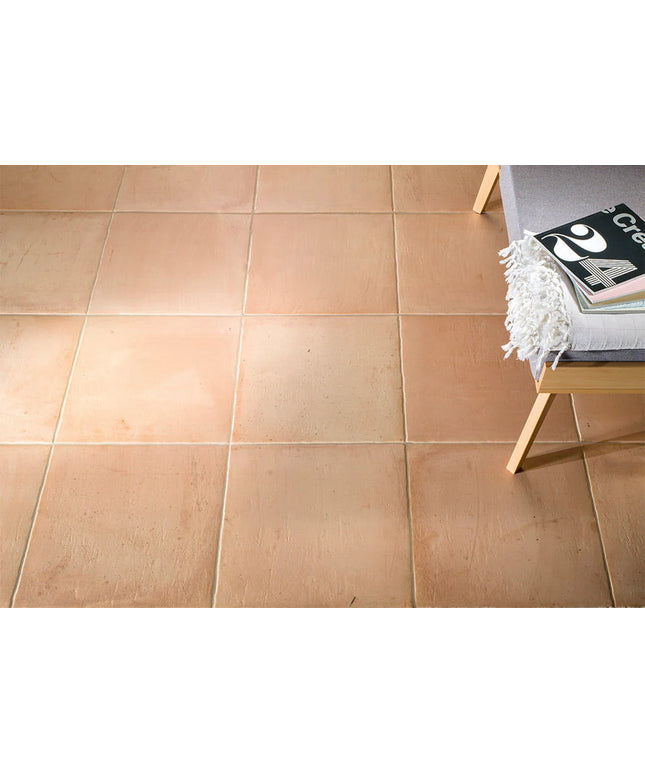 Beige tiles on a floor with a small table and chair in the corner.