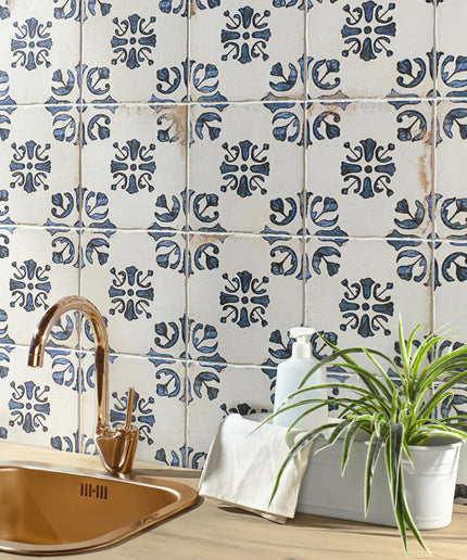 Kitchen with blue and white patterned tiles, copper sink, and plant.