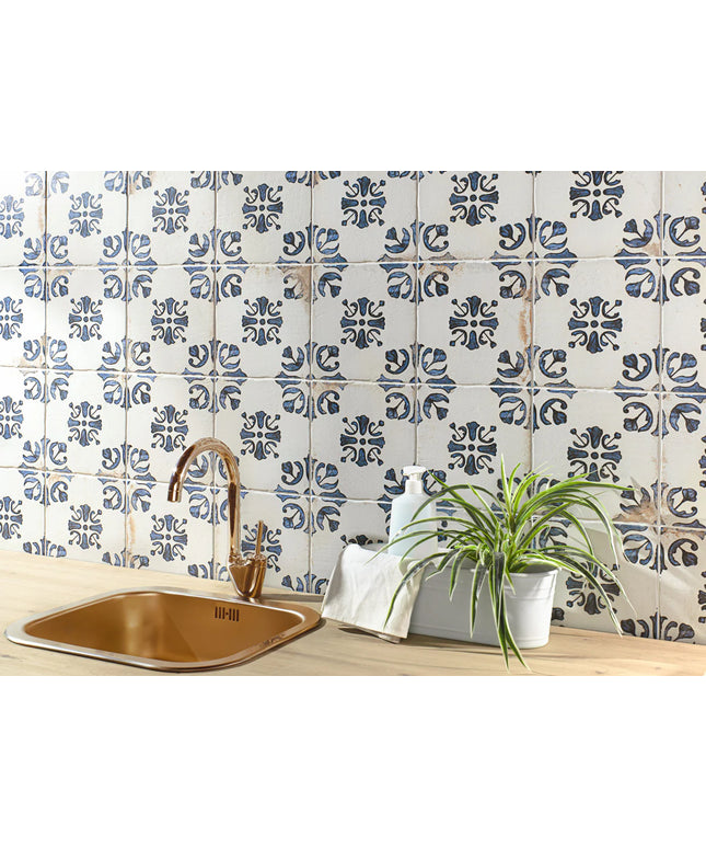 Kitchen with blue and white patterned tiles, copper sink, and plant.