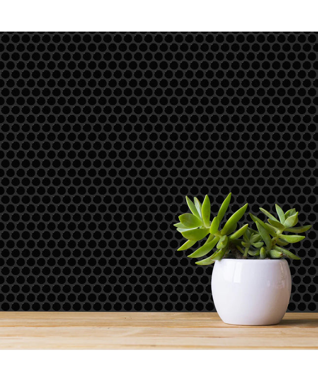 White pot with green succulents on a wooden surface against a black honeycomb patterned wall.