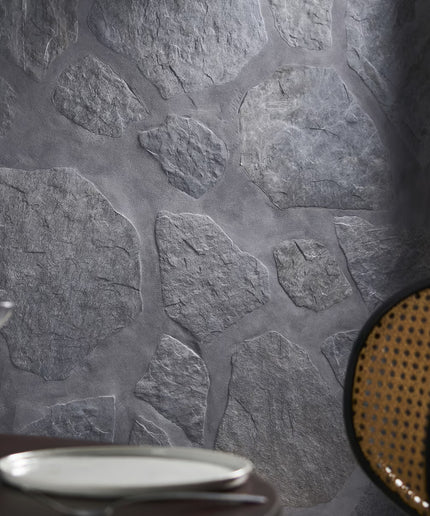 Close-up of a stone-textured wall with a plate and chair in the foreground