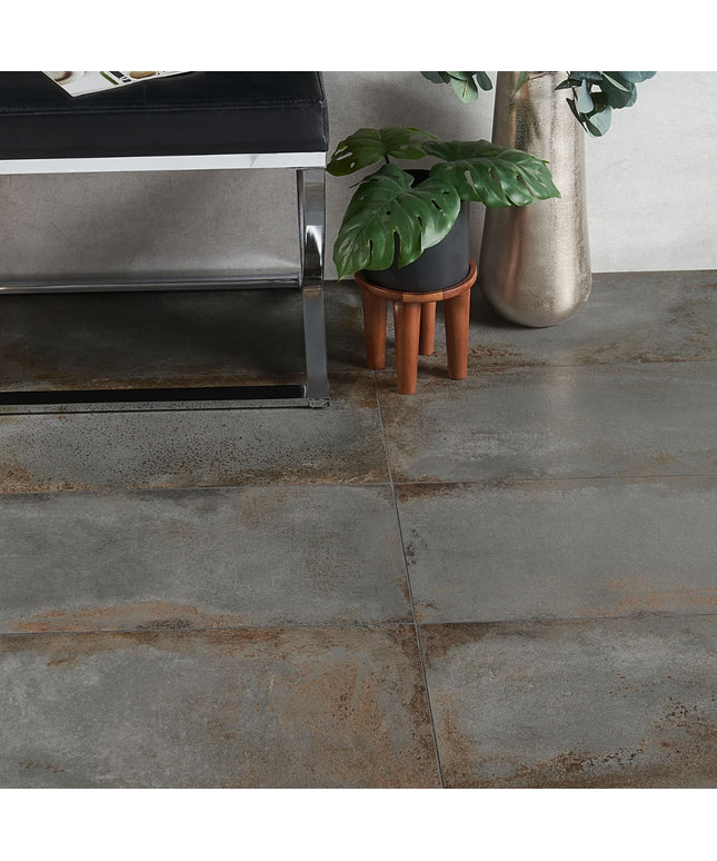 Close-up of a tiled floor with a metallic object and potted plants in the background.