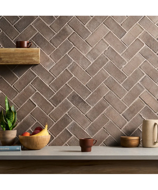 Herringbone patterned wall with decorative items on a shelf and table.