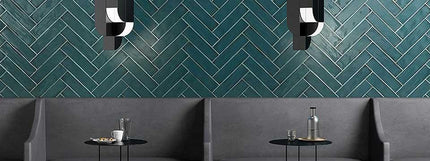 Modern interior with a green herringbone patterned wall, gray sofa, and small round table.
