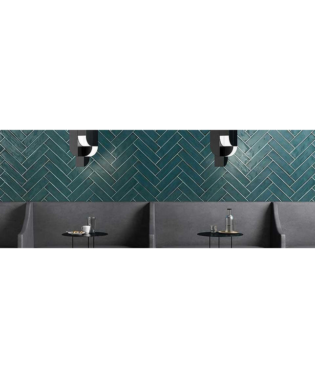 Modern interior with a green herringbone patterned wall, gray sofa, and small round table.
