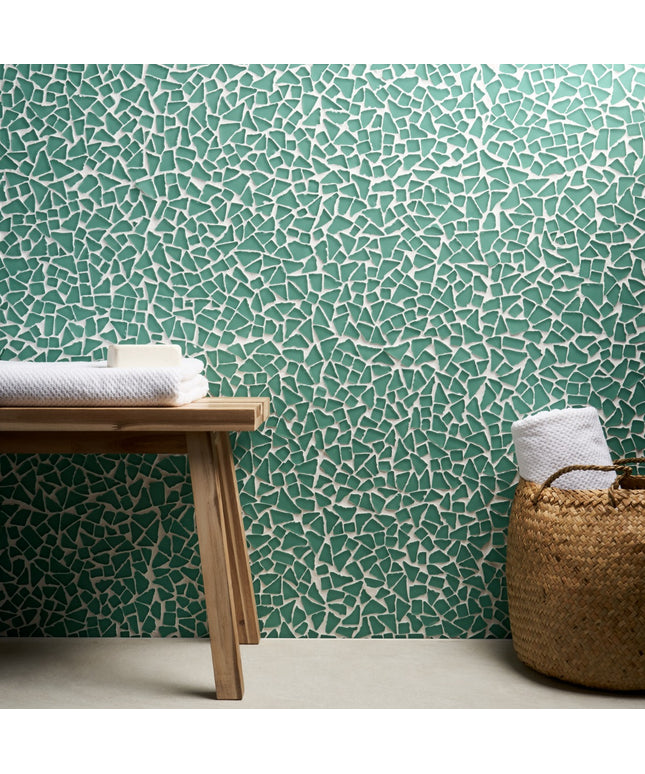 Mosaic patterned wall with wooden bench and basket containing towels.