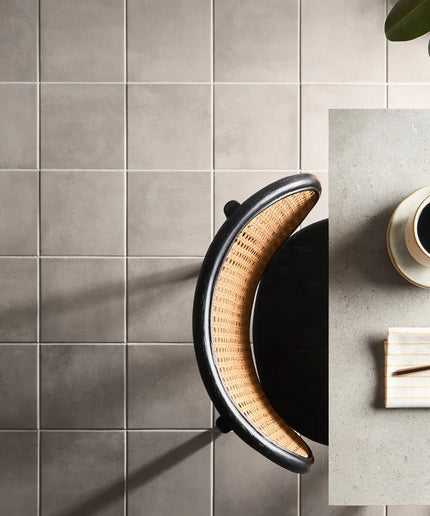 Modern kitchen with gray tiled wall and a coffee setup on a table.
