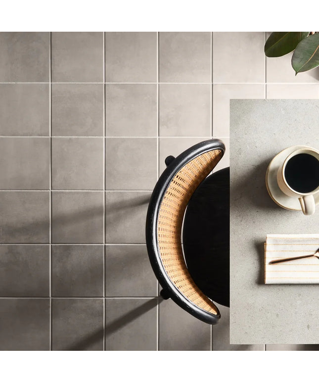 Modern kitchen with gray tiled wall and a coffee setup on a table.