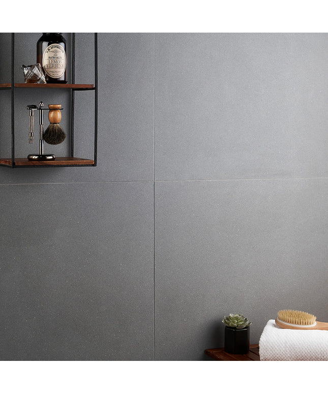 Gray tiled wall with a wooden shelf and decorative items.