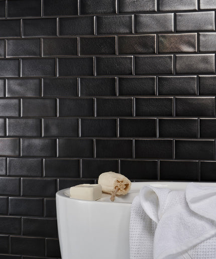 Black tiled wall with a white sink and towel