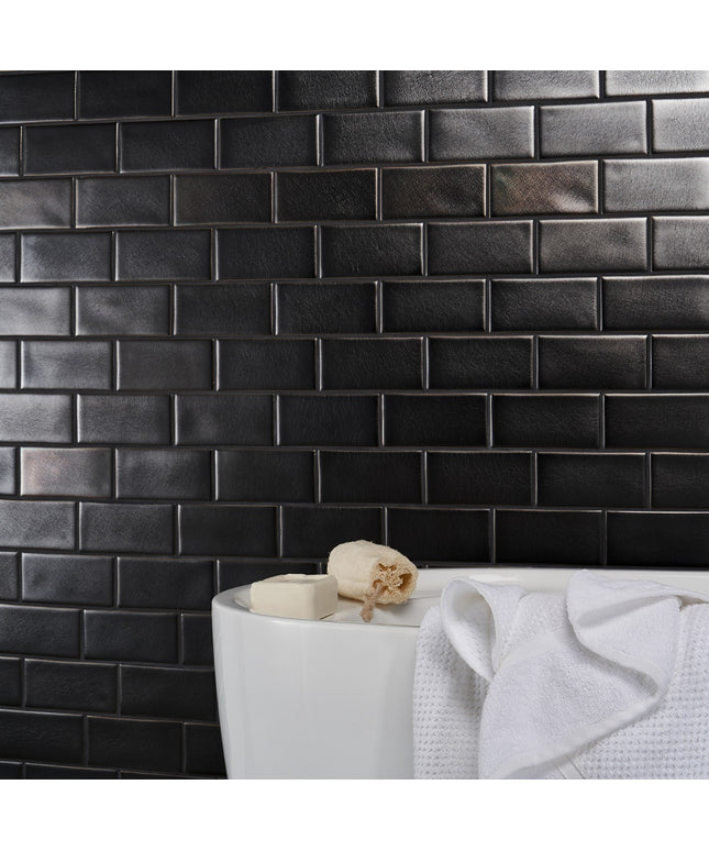Black tiled wall with a white sink and towel