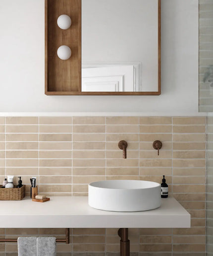 Modern bathroom with a white sink, wooden mirror, and beige tiles.