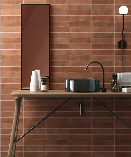 Bathroom vanity with black sink and faucet against a tiled wall.
