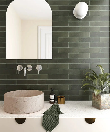 Bathroom with green tiled wall, white sink, and decorative elements.