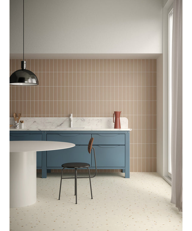 Modern kitchen with vertical beige backsplash tiles, blue cabinets, terrazzo floor, round table