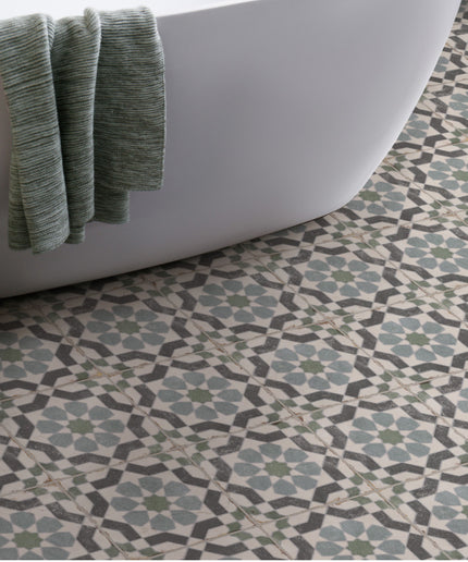 Patterned floor tiles in bathroom with white tub, green towel and basket of towels
