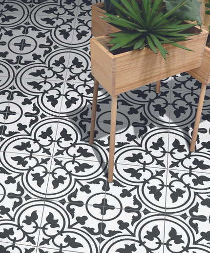 Black and white patterned floor tiles with geometric design and wooden planters with green plants.
