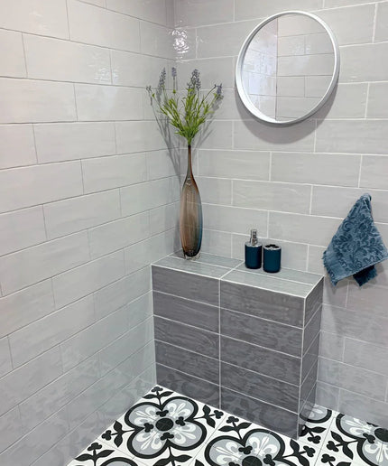 Glossy gray subway wall tiles with patterned black and white floor tiles in a modern bathroom
