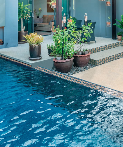 Modern outdoor pool with decorative patterned pool tiles, surrounded by patio plants.