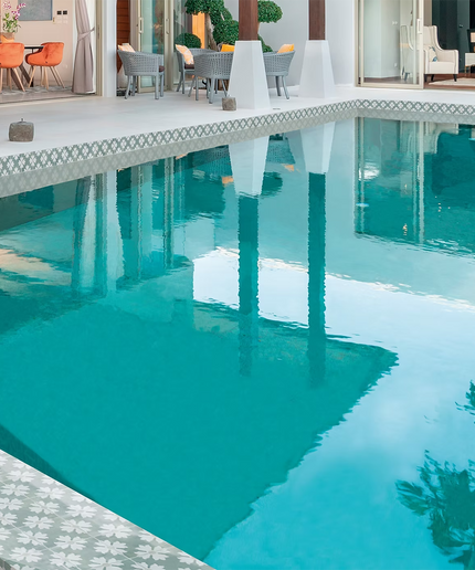 Modern swimming pool with patterned decorative tiles and outdoor seating area