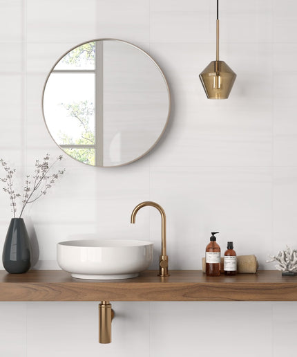 Bathroom setup with a round mirror, wooden vanity, white sink, and gold fixtures.