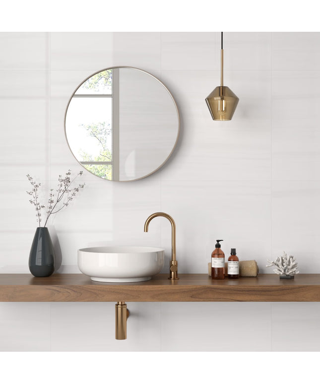 Bathroom setup with a round mirror, wooden vanity, white sink, and gold fixtures.