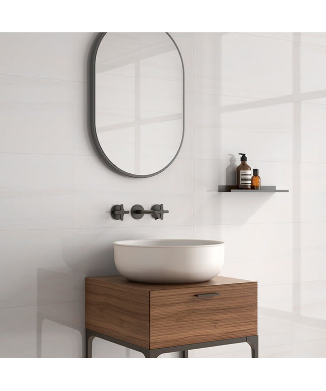 Bathroom vanity with wooden cabinet, white sink, and round mirror on a white wall.