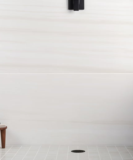 White tiled wall with a small wooden stool and black object in the corner
