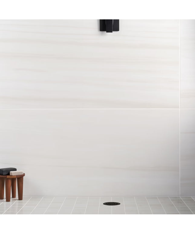 White tiled wall with a small wooden stool and black object in the corner