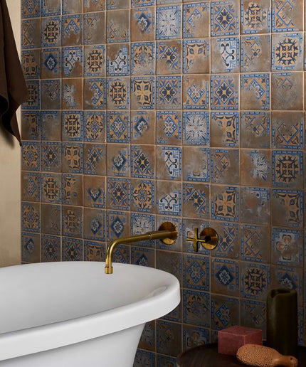 Bathroom with a freestanding bathtub against a tiled wall with decorative patterns.