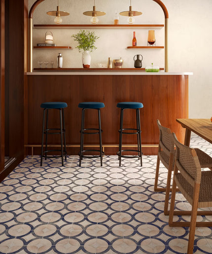 Modern bar interior with wooden counter, stools, and patterned floor.