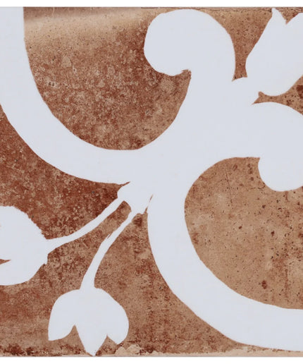 Decorative tile with white floral design on a brown background