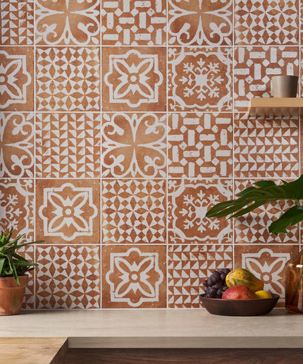 Patterned tiles on a wall with decorative elements and plants.