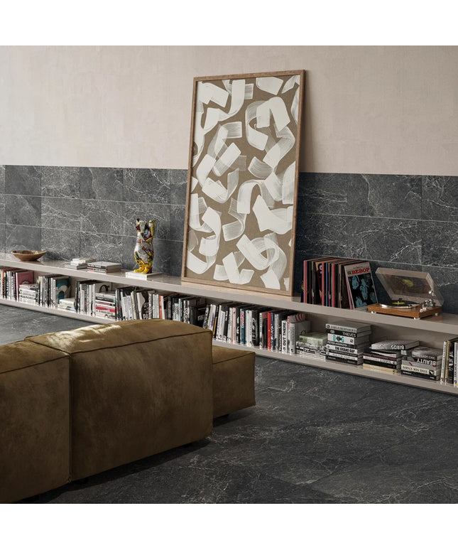 Living room with a bookshelf, brown ottoman, and abstract art on a gray marble floor.