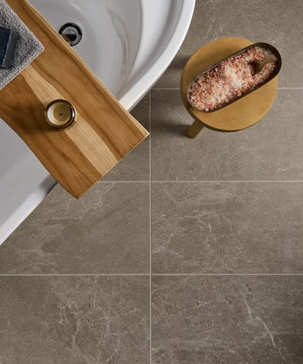 Bathroom setting with a wooden shelf, bath, and salt lamp on a tiled floor.