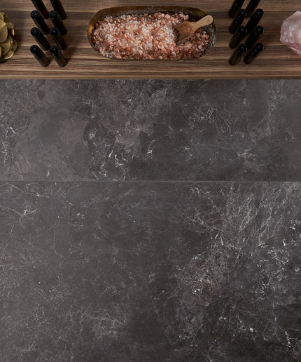 Dark stone surface with decorative items including a bowl of pink salt, a wooden spoon, and a crystal.