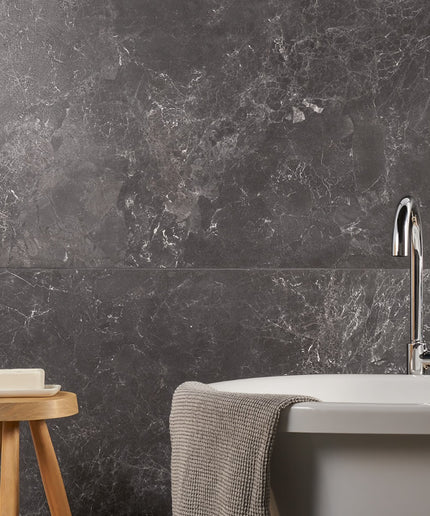 Bathroom with dark marble wall, sink, and wooden stool.