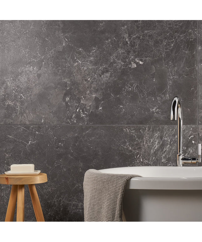 Bathroom with dark marble wall, sink, and wooden stool.