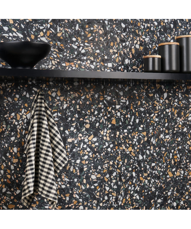 Terrazzo-patterned wall with black shelf, striped towel, and cylindrical objects.