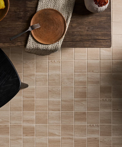 Close-up of a tiled floor with a wooden table and chair in the background.