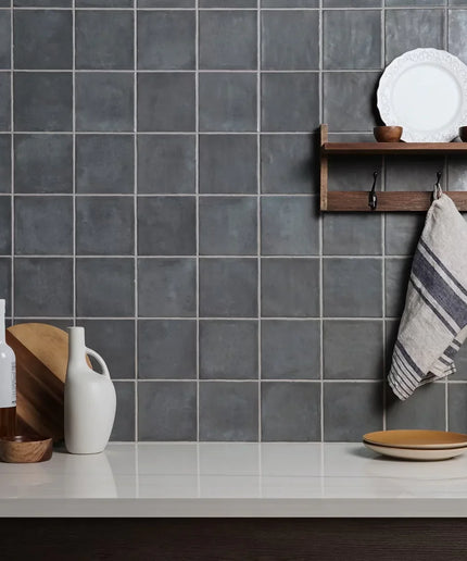 Kitchen with gray tiled wall, wooden shelf, and various kitchen items.